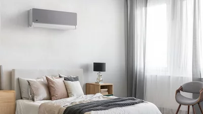 Remko Klimagerät an der Wand in einem hellen Schlafzimmer mit Bett und Vorhängen
