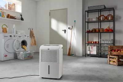 Déshumidificateur blanc Remko dans un local technique lumineux, à côté d'une machine à laver.