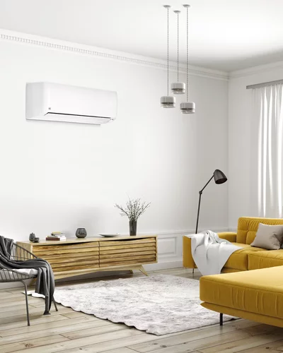 Weißes Wandgerät einer Klimaanlage in einem modernen Wohnzimmer mit gelbem Sofa und Holzregal.