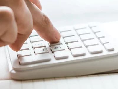 Taschenrechner auf einem Schreibtisch Jemand bedient einen auf dem Schreibtisch liegenden Taschenrechner