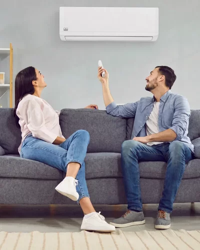 Een paar zit op een bank en bedient een Remko wandluchtbehandelingsunit met een afstandsbediening.