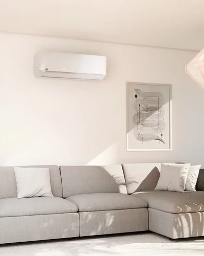 Bright living room with a grey sectional sofa and a white Remko wall-mounted air conditioner.