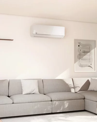 Bright living room with a grey sectional sofa and a white Remko wall-mounted air conditioner.