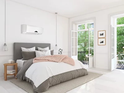 Chambre avec climatiseur mural blanc au-dessus du lit et fenêtres ouvertes