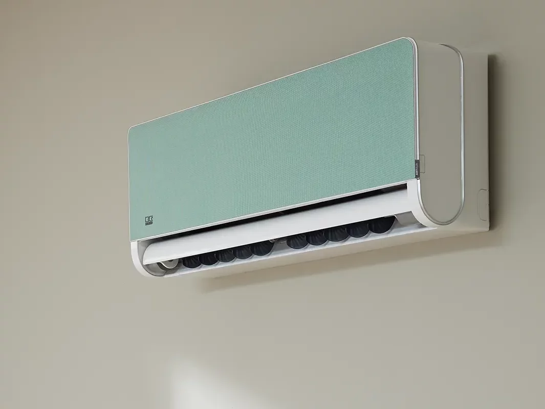 Klimawandgerät mit mintgrüner Blende an Wand