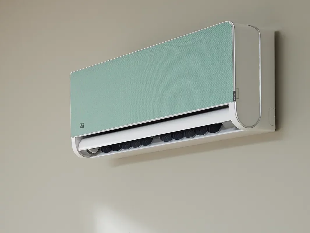 Klimawandgerät mit mintgrüner Blende an Wand