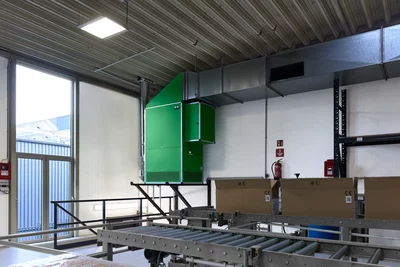 Groene Remko-apparaat aan plafond gemonteerd met luchtkanalen boven transportband in magazijn