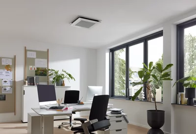 Ceiling air conditioning unit in a modern office with desks and windows