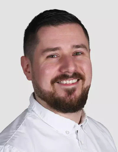 Matthias Horstschäfer Porträt eines lächelnden Mannes mit Bart und weißem Hemd vor neutralem Hintergrund