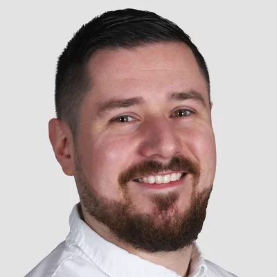 Matthias Horstschäfer Porträt eines lächelnden Mannes mit Bart und weißem Hemd vor neutralem Hintergrund
