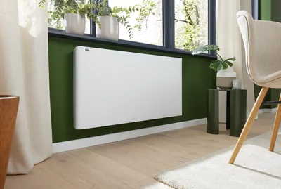 White Remko electric panel heater mounted on a green wall under a window.