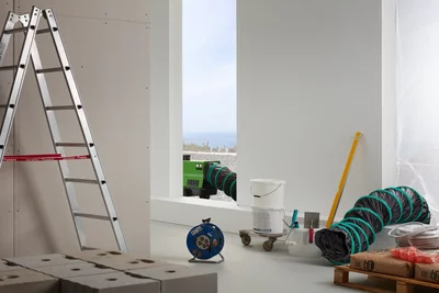 Remko device with green duct on a construction site next to a ladder and building materials